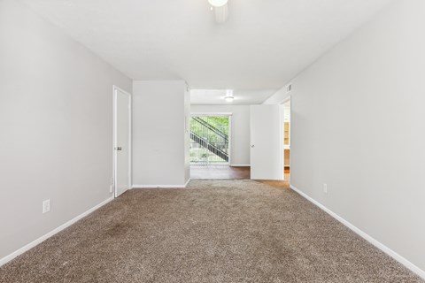 a spacious living room with carpet and white walls
